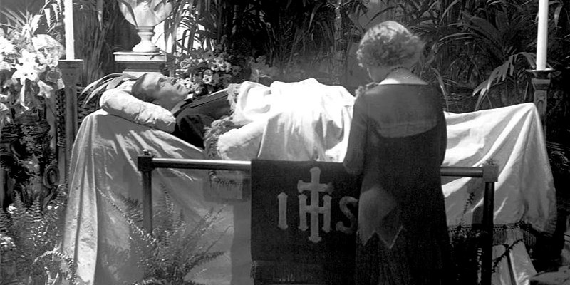 Una donna in ginocchio prega davanti alla bara di Rodolfo Valentino